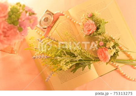 英語の本の上に飾られた花束と香水の瓶の写真の写真素材