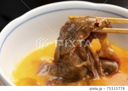 すき焼きの肉に溶き卵をつけて食べる すき焼きの肉に溶き卵をつけて食べる 75315778