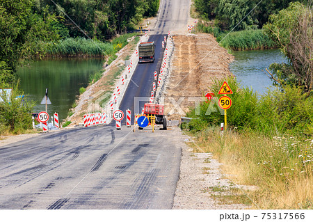 Road repair on the dam across the small river Road repair on the dam across the small river 75317566