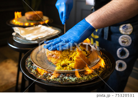 Shah's pilaf. Serving and cutting Khan's pilaf in lavash in Azerbaijani style in the restaurant. Traditional Oriental dish Shah's pilaf. Serving and cutting Khan's pilaf in lavash in Azerbaijani style in the restaurant. Traditional Oriental dish 75320531