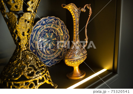 Old copper jug from the east on a black background Old copper jug from the east on a black background 75320541