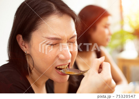 Woman eats spicy hot tomyum noodle soup and hanging on chopstick 75320547