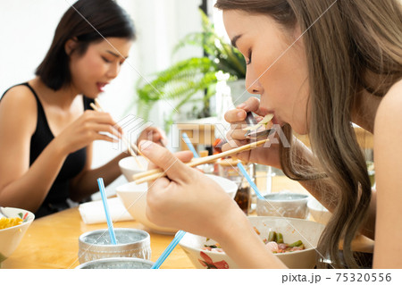 Woman eats spicy hot tomyum noodle soup and hanging on chopstick Woman eats spicy hot tomyum noodle soup and hanging on chopstick 75320556