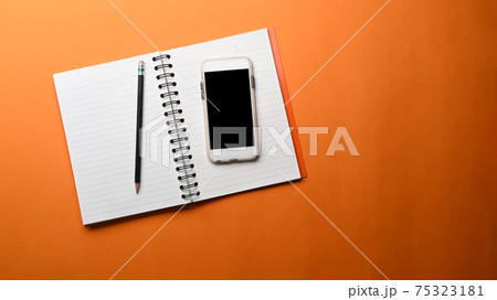 Mock up smart phone with blank screen, empty notebook and copy space on orange background. Mock up smart phone with blank screen, empty notebook and copy space on orange background. 75323181