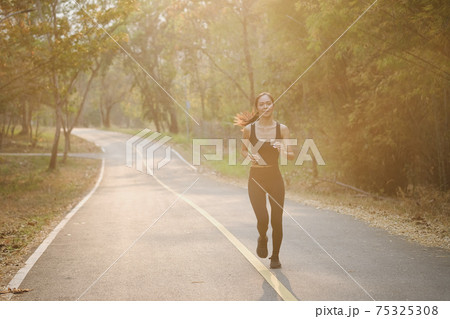 Young woman in sportswear jogging at park in the morning. 75325308