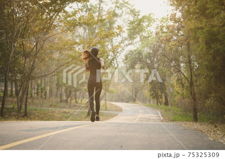 Healthy young woman jogging during outdoor workout in the park. 75325309