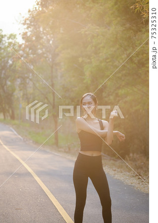 Portrait of sportswoman stretching before before jogging at park. 75325310