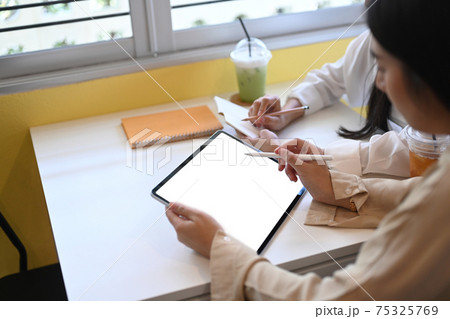 Two young woman designer discussing ideas of project on digital tablet. Two young woman designer discussing ideas of project on digital tablet. 75325769