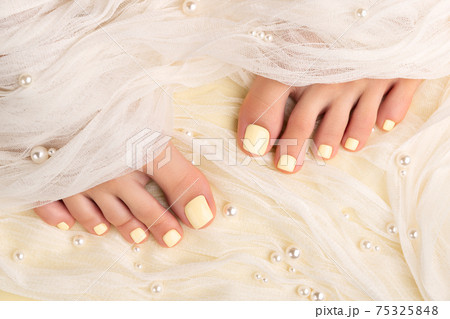 Beautiful womans legs with summer nail design on yellow fabric 75325848