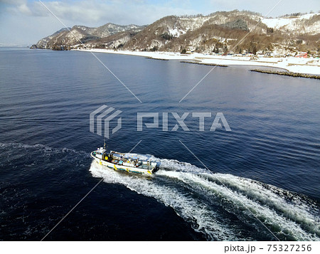 早春の北海道豊浦町大岸漁港から出漁する漁船の風景を空撮 75327256