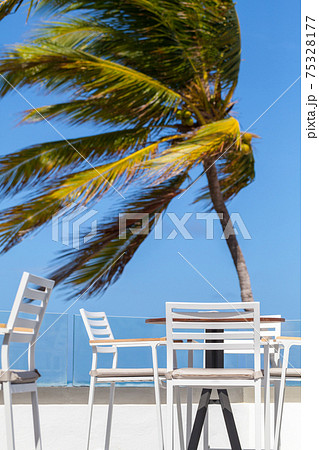 Empty white chairs and a table are on a beach Empty white chairs and a table are on a beach 75328177