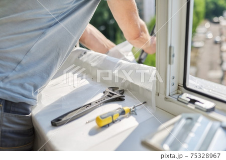 Installing an air conditioner in an apartment office, close-up of an technician hands 75328967