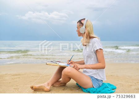 Teenager girl in headphones drawing with watercolors marine sketch 75329663