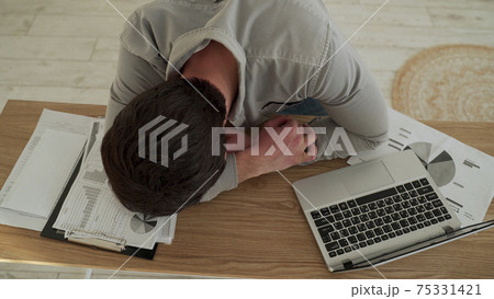 Businessman tired overworked he sleeping over a laptop computer on the desk. Tired young man sleeping in his office 75331421