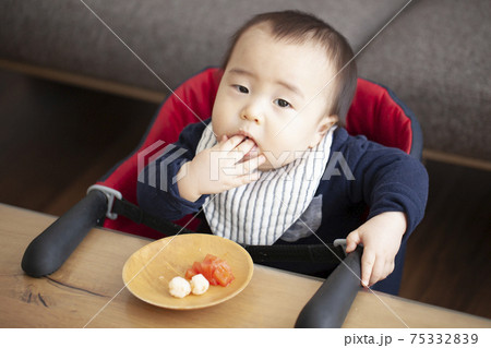 手づかみで離乳食を食べる赤ちゃんの写真素材