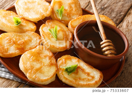 Sweet Tiganites Greek traditional pancakes with honey closeup in the plate. Horizontal Sweet Tiganites Greek traditional pancakes with honey closeup in the plate. Horizontal 75333607