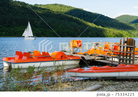 Orange catamarans on lake moored at the pier. Hipster lifestyle. Active summer vacation. 75334225
