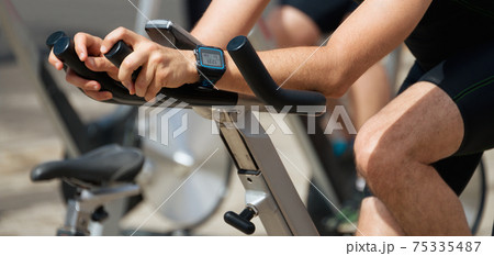 Active people working out on exercise stationary bicycle Active people working out on exercise stationary bicycle 75335487