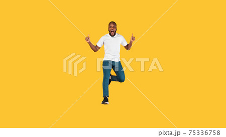 Emotional Black Guy Jumping Gesturing Thumbs Up Over Yellow Background Emotional Black Guy Jumping Gesturing Thumbs Up Over Yellow Background 75336758