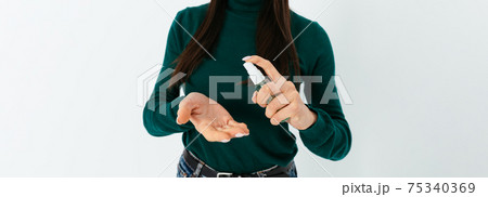 Young woman applying alcohol sanitizer on her hands to prevent spread of virus Young woman applying alcohol sanitizer on her hands to prevent spread of virus 75340369