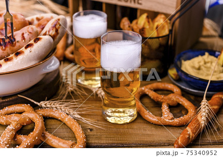 Fresh craft beer. German sausages on the grill. Traditional German sausages and pastry brezel for a Fresh craft beer. German sausages on the grill. Traditional German sausages and pastry brezel for a 75340952
