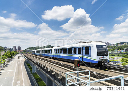 Wenhu or Brown line of Taipei Metro in Taipei, Taiwan. View of a train traveling on elevated rails of Taipei Metro System between office towers under the blue clear sky. Wenhu or Brown line of Taipei Metro in Taipei, Taiwan. View of a train traveling on elevated rails of Taipei Metro System between office towers under the blue clear sky. 75341441