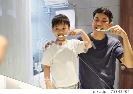 Father and son brushing teeth 75342404
