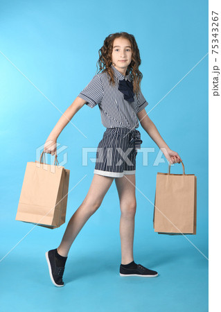Child with a packet isolated on blue background. Holiday present, shopping. Kid happy shopping in mall. Child with a packet isolated on blue background. Holiday present, shopping. Kid happy shopping in mall. 75343267