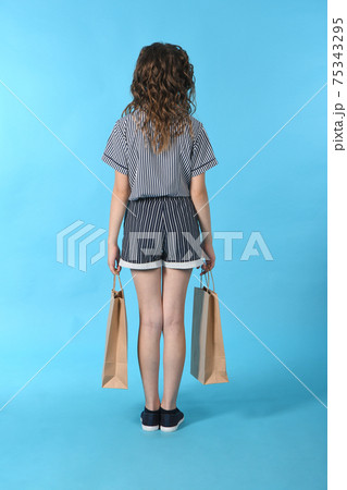 Child with a packet isolated on blue background. Holiday present, shopping. Kid happy shopping in mall. Child with a packet isolated on blue background. Holiday present, shopping. Kid happy shopping in mall. 75343295