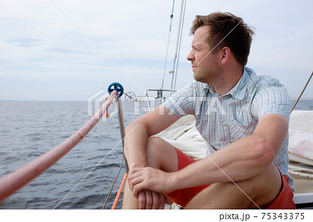 Man sitting on boat sailing on ocean being happy and carefree 75343375