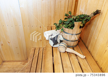 Interior details Finnish sauna steam room with traditional sauna accessories basin birch broom scoop felt hat towel. Traditional old Russian bathhouse SPA Concept. Relax country village bath concept. Interior details Finnish sauna steam room with traditional sauna accessories basin birch broom scoop felt hat towel. Traditional old Russian bathhouse SPA Concept. Relax country village bath concept. 75343896