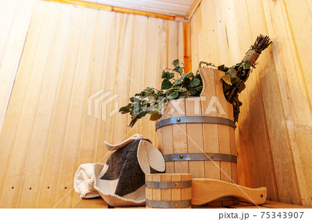 Interior details Finnish sauna steam room with traditional sauna accessories basin birch broom scoop felt hat towel. Traditional old Russian bathhouse SPA Concept. Relax country village bath concept. 75343907