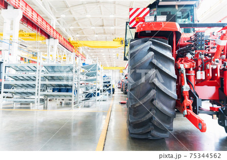 Blurred assembly workshop and tractor wheel at big industrial plant Blurred assembly workshop and tractor wheel at big industrial plant 75344562