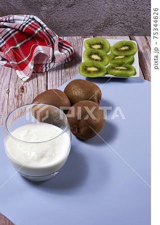 Glass with yoghurt and broken kiwis on a plate Glass with yoghurt and broken kiwis on a plate 75344626
