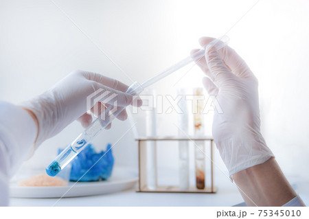 Hands in protective gloves holding test tube making chemistry experiment 75345010