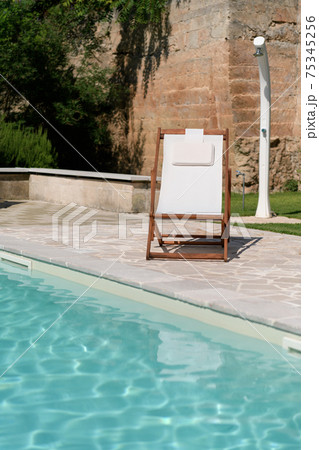 Swim pool with clear blue water and one sun bed on sunny day in a yard Swim pool with clear blue water and one sun bed on sunny day in a yard 75345256