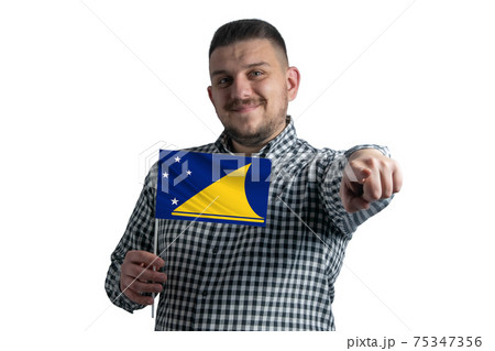 White guy holding a flag of Tokelau and points forward in front of him isolated on a white background White guy holding a flag of Tokelau and points forward in front of him isolated on a white background 75347356