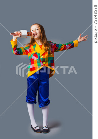 Little singer girl with microphone over grey background Little singer girl with microphone over grey background 75348538