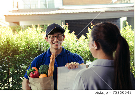 Supermarket food delivery staff deliver bags to female customers in front of the house. Supermarket food delivery staff deliver bags to female customers in front of the house. 75350645