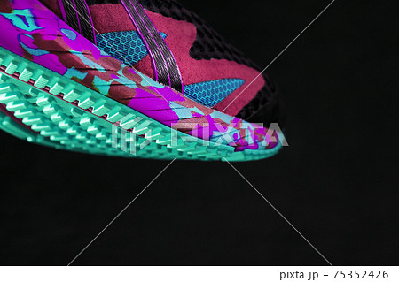 A sporty running shoe with a textured green sole on a black background. A sporty running shoe with a textured green sole on a black background. 75352426