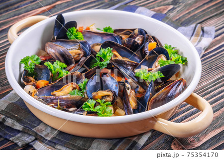Boiled mussels in cooking dish with parsley on a wooden background Boiled mussels in cooking dish with parsley on a wooden background 75354170