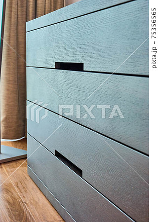 Modern wooden chest of drawers of finger pull design closeup 75356565