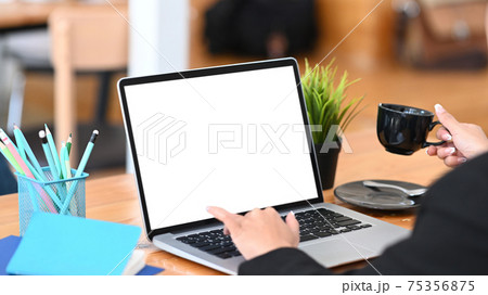 Close up view of businesswoman holding a cup of coffee and working on computer laptop. 75356875