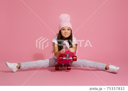 child girl laughing and sitting on pink skateboard child girl laughing and sitting on pink skateboard 75357832