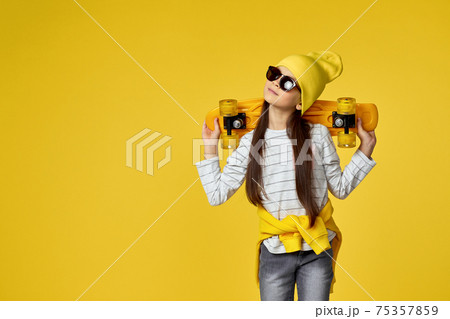 child girl in hat and sunglasses with yellow skateboard 75357859
