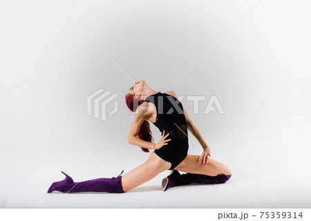 Young beautiful flexible female in black jumpsuit and high heels is posing in a dance studio. Young beautiful flexible female in black jumpsuit and high heels is posing in a dance studio. 75359314