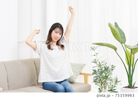 部屋のソファに座って深呼吸をする若い女性 75359963