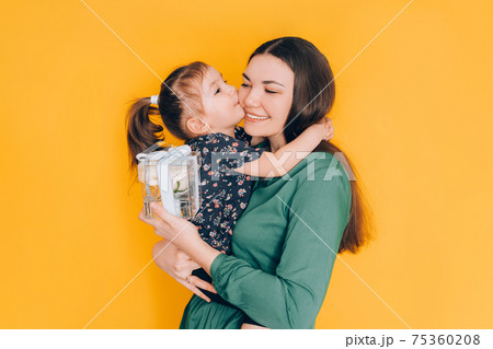 Daughter gives gift to her mother. Congratulations to the parents on the holiday Daughter gives gift to her mother. Congratulations to the parents on the holiday 75360208