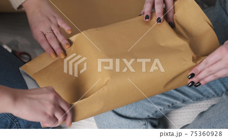 Two young woman wrapping Christmas present 75360928