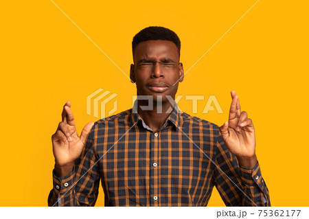 Making wish. Superstitious african american guy keeping his fingers crossed 75362177
